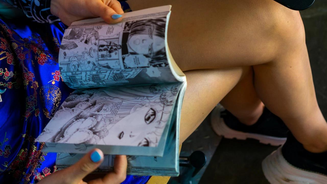 Woman reading manga crosslegged.